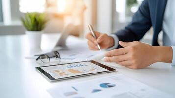 A diverse team gathered around a table, analyzing charts and graphs on a tablet in a sleek office setting photo