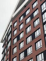 moderno ladrillo edificio con angular ventanas debajo nublado cielo demostración arquitectura estilo foto