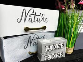 Decorative storage boxes with 'Nature' text and 'Home' block during floral arrangement. photo