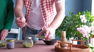 man teaching woman making Japanese matcha tea, sieving matcha powder into the bowl video