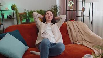 Tired lazy woman enjoy relaxing on home sofa resting napping after hard working day, closed her eyes video