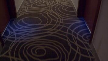 Person walks down a dark hotel corridor, surrounded by empty spaces and soft shadows, creating a tranquil atmosphere video