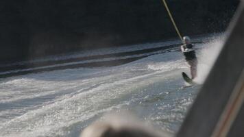 Woman water skiing on a lake creates a large wake while friends watch from a boat, enjoying a sunny summer day video