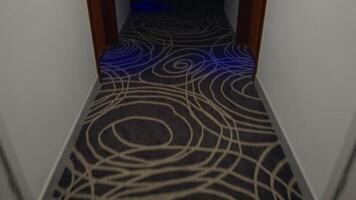 Emergency lighting switching between bright and dark states inside hotel corridor, highlighting patterned carpet and creating dramatic visual contrast of illumination video