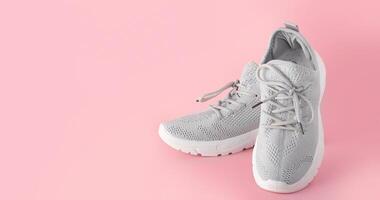 New comfortable sneakers, gray sports shoes with laces on a colored pink background with copy space photo