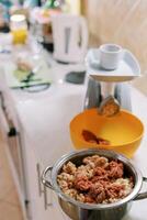 Minced meat in a saucepan on the table next to the electric meat grinder photo