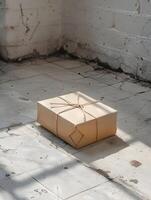 A rectangular box covered in brown paper rests on the hardwood floor photo