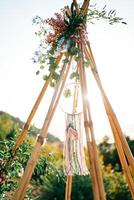 Sun shines through the top of a wedding tipi arch in the mountains photo
