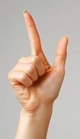 A womans arm is raised, index finger pointing up in a gesture photo