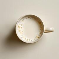 A cup of milk rests on a porcelain dishware on the table photo