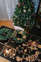 Accessories for the New Year wreath lie on the table near the decorated Christmas tree photo