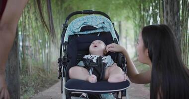 Two Asian women play with baby boy in a baby stroller outside a coffee shop. A relaxing atmosphere with a warm moment. video