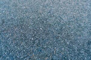 Texture of gray asphalt with small blades of grass lying on it photo