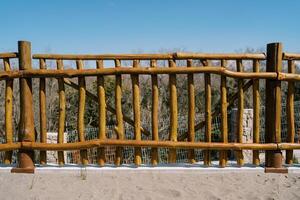 Wooden rustic fence in the park against the background of green trees and blue sky photo