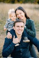 Smiling mother hugs a little girl from behind on her father shoulders. Portrait photo