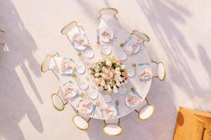 Festive round table with chairs stands in an open area. Top view photo