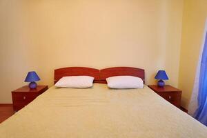 Small lamps with lampshades stand on the nightstands on the sides of the double bed photo