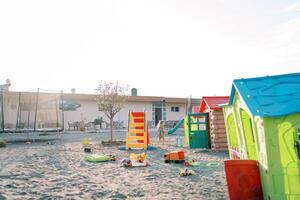 Little girl goes to the slides on the playground past the toy houses. Back view photo