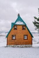 Wooden cottage with a green roof in a snowy mountain valley photo