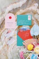Colorful invitations with name cards and a bouquet of flowers lie on a marble tabletop photo