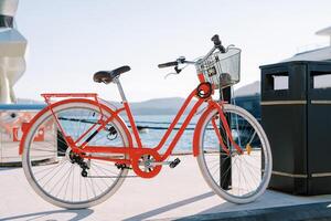 Rental red bicycle with basket attached to a pole on the boardwalk photo