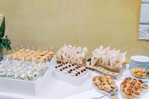 Festive table with appetizers, portioned salads, mini-burgers and cakes photo