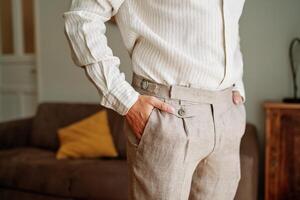 Groom stands in the room with his hands in his trouser pockets. Cropped. Faceless photo