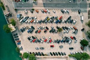 Large parking lot with colorful cars standing in rows on the seashore. Drone photo