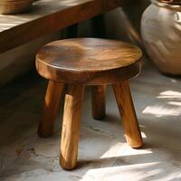 A wooden bar stool rests on the flooring by a window sill photo
