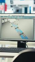 Vertical PC screen on desk in photovoltaics factory used to update software of robot arms placing solar panels on assembly lines. Computer monitor in empty facility used for upgrading solar plant machinery video