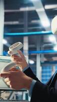 Vertical Photovoltaics factory worker monitors system performance using virtual reality tech. Solar panels manufacturing plant employee using VR headset to track energy production and efficiency, camera A video