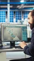 Vertical Photovoltaics factory worker monitors system performance, drinking coffee. Solar panels manufacturing plant employee enjoys beverage while using PC to track energy production and efficiency, camera A video