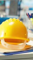 Vertical Yellow hardhat next to PC screen in photovoltaics factory used to update software of robot arms placing solar panels on assembly lines. Close up of engineering gear in empty solar plant facility video