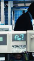 Vertical Masked worker in photovoltaics factory commits corporate espionage, stealing proprietary technology using USB stick. Man exploits insider access to copy trade secrets from solar panel plant, camera B video