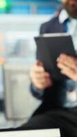 Vertical Photovoltaics factory employee uses tablet to review performance of robot arms placing solar panels on assembly lines. Specialist sitting on desk uses device to inspect solar plant machinery, camera B video