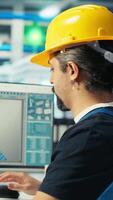 Vertical Photovoltaics factory engineer using artificial intelligence to monitor performance of robot arms placing solar panels on assembly lines. Expert using AI tech to inspect solar plant machinery video