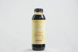 Beautifully designed honey bottle with a rustic label, placed beside a honey dipper and a bowl of fresh fruit photo