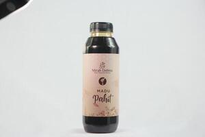 A bottle of black liquid with a white background photo