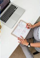 A woman working on a laptop with a whiteboard and a pen photo