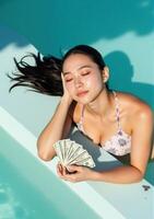 A woman in a bikini laying on a pool with money photo