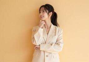 Asian woman in business suit standing against yellow wall photo