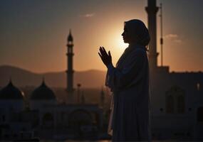 A muslim woman praying at sunset in front of a mosque photo