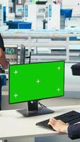 Vertical Photovoltaics factory worker monitors system performance on green screen PC. Solar panels manufacturing plant employee using chroma key computer to track energy production and efficiency, camera A video