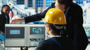 Solar panel manufacturing plant manager showing engineer on PC how to develop prototypes for new solar energy systems. Team leader telling technician about new photovoltaics materials, camera B video