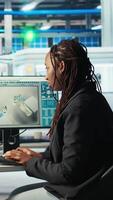 Vertical Programmer in photovoltaics factory using PC program to diagnose malfunctioning systems. Woman coding at computer desk in solar panels manufacturing plant, reducing downtime, camera A video