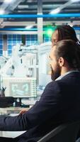 Vertical Photovoltaics factory manager giving tasks to workers, asking them to adjust system parameters. Team leader telling employees how to optimize energy supply in solar panel manufacturing plant, camera A video