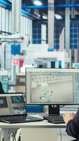 Vertical Photovoltaics factory technician adjusts system parameters on laptop to maximize solar cells power generation. Man using notebook optimizing energy supply in solar panel manufacturing plant, camera A video