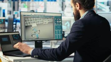 Photovoltaics factory technician adjusts system parameters on laptop to maximize solar cells power generation. Man using notebook optimizing energy supply in solar panel manufacturing plant, camera B video