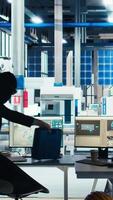 Vertical Masked hacker sneaking into solar panel plant at night, inserting USB stick into computer to steal confidential manufacturing data. Thief in photovoltaics factory extracts company files, camera A video