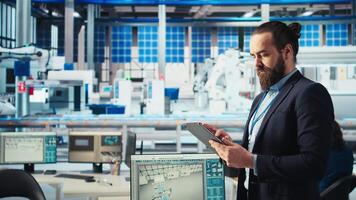 Portrait of engineer in photovoltaics factory using tablet to diagnose malfunctioning systems. Solar panels manufacturing plant worker reduces downtime and maintains operational reliability, camera A video